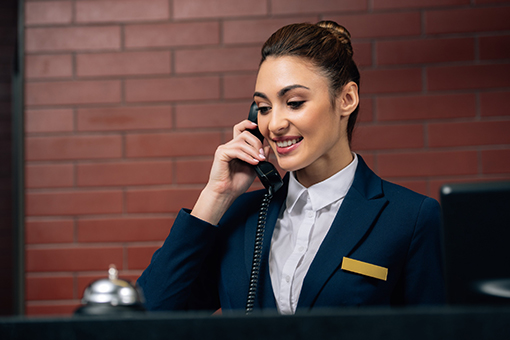 Receptionist in Miami Florida Smiling While Using New Hotel Phone Systems